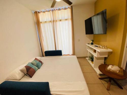 Kleines Zimmer mit einem Bett und einem TV in der Unterkunft COZY UNIT at Bambu Residencial & AMAZING POOL in Puerto Vallarta
