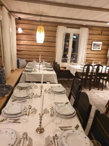uma sala de jantar com mesas com pratos brancos e velas em Billingen Seterpensjonat em Skjåk