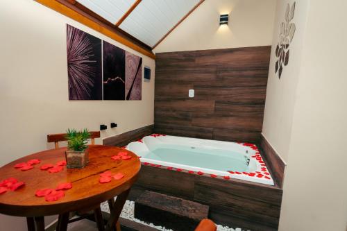 uma banheira num quarto com uma mesa em Pousada Villa Pinhal em Santo Antônio do Pinhal