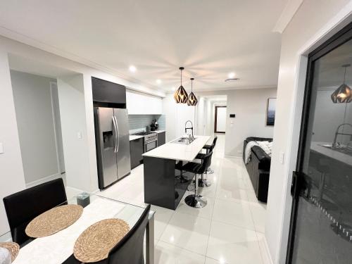 uma cozinha e sala de estar com mesa e cadeiras em Plantation Retreat 4 Bedroom Modern Home em Landsborough
