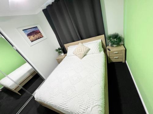 a small bedroom with a bed and a green wall at Plantation Retreat 4 Bedroom Modern Home in Landsborough