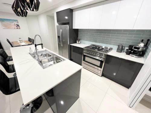 a white kitchen with a sink and a stove at Plantation Retreat 4 Bedroom Modern Home in Landsborough