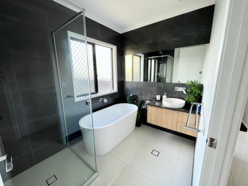 a bathroom with a bath tub and a sink at Plantation Retreat 4 Bedroom Modern Home in Landsborough