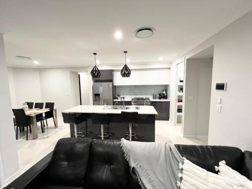 a living room with a couch and a kitchen at Plantation Retreat 4 Bedroom Modern Home in Landsborough