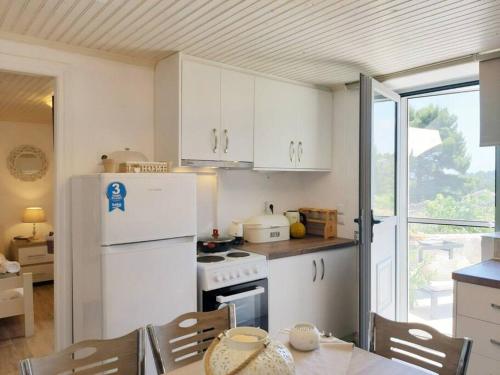 Il comprend une cuisine équipée d'un réfrigérateur blanc et d'une table. dans l'établissement Sunrise cottage, à Gaios