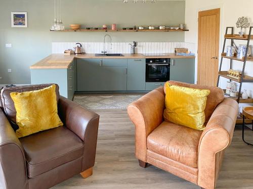 a living room with two chairs and a kitchen at Glan Llyn Annex in Whitford