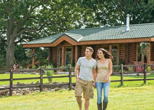 a man and a woman walking in front of a cabin at Sun Hill Lodges in Constable Burton