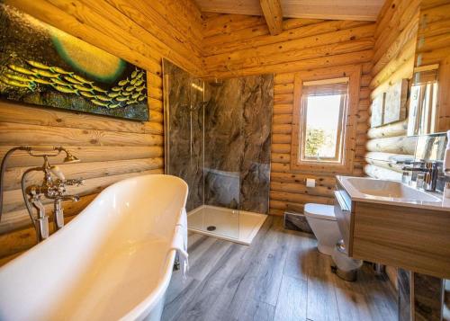 a bathroom with a tub and a sink in a log cabin at Sun Hill Lodges in Constable Burton