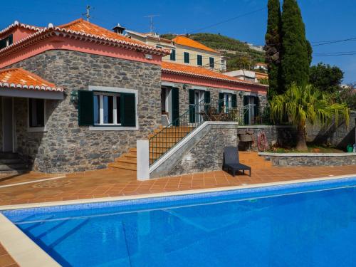 a house with a swimming pool in front of a house at Vivenda Por do Sol in Ponta do Sol