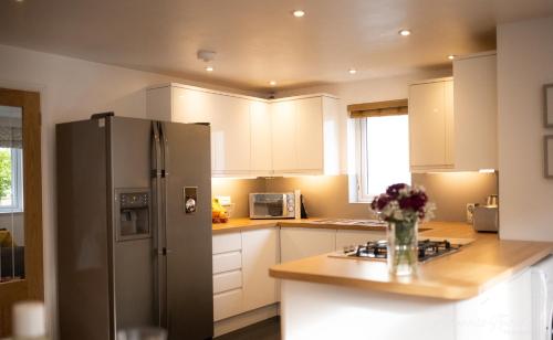 a kitchen with white cabinets and a stainless steel refrigerator at The Lookout, Modern Home from Home, Sleeps 5, with private parking & outside terrace in St Ives