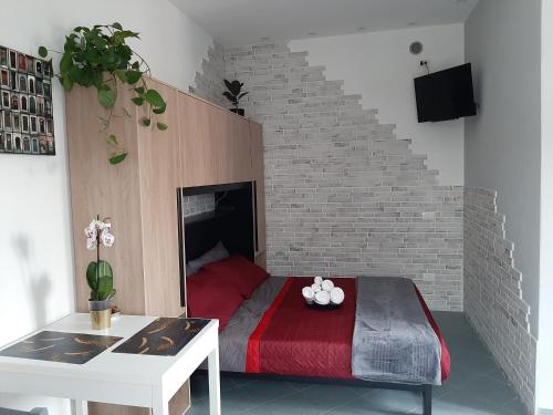 a bedroom with a red bed and a brick wall at Vinessa Home in Peschiera del Garda