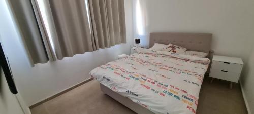 a white bedroom with a bed and a window at 3 חדרים קרקע באפרסק in Eilat