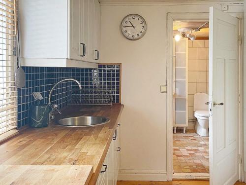 una cocina con fregadero y un reloj en la pared en Holiday home ÅKERSBERGA V, en Åkersberga