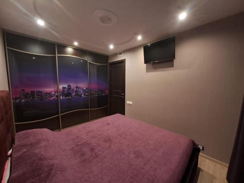 a bedroom with a purple bed and a flat screen tv at Good J&I apartment in Balvi