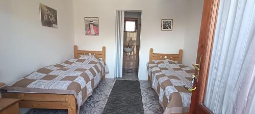 a room with three beds and a door to a bathroom at Zempléni Szellő Vendégház in Vilyvitány