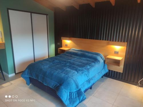 um quarto com uma cama com um edredão azul em Elordi em San Martín de los Andes