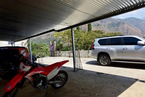una moto rossa parcheggiata accanto a un SUV bianco di CASA EL ROBLE a San Juan La Laguna