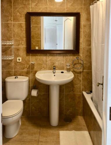 a bathroom with a sink and a toilet and a mirror at Light House in Corralejo