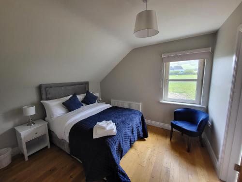 una camera da letto con un letto con una sedia blu e una finestra di Dunquin House Bed and Breakfast a Dunquin