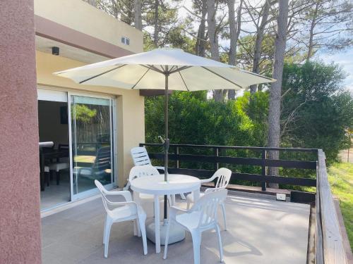 una mesa y sillas con una sombrilla en el patio en Ubatuba 3 - dept 1 habitación en Balneario Mar Azul