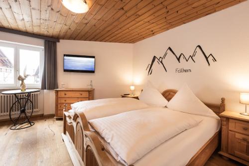 a bedroom with a bed and a tv on the wall at Landgasthof Augustiner in Oberstdorf