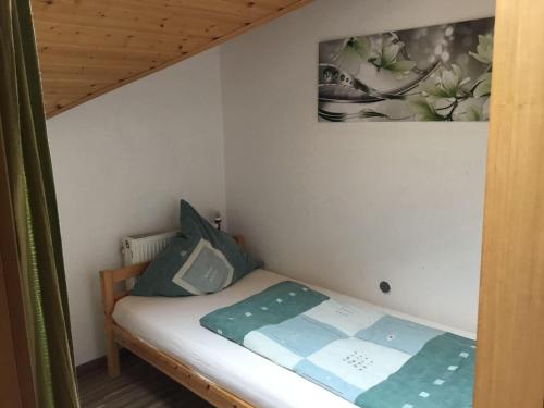 ein kleines Bett in einem Zimmer mit einem Bild an der Wand in der Unterkunft Haus Fechtig, Wohnung Typ B in Bonndorf im Schwarzwald