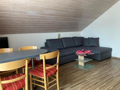 ein Wohnzimmer mit einem blauen Sofa und einem Tisch in der Unterkunft Haus Fechtig, Wohnung Typ B in Bonndorf im Schwarzwald