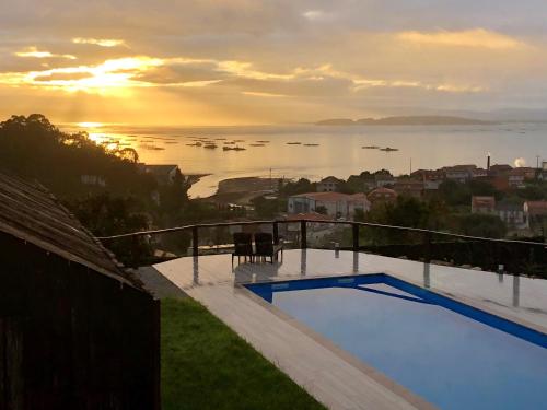a view of the ocean from a house with a swimming pool at Cabañas Rias Baixas in Pobra do Caramiñal