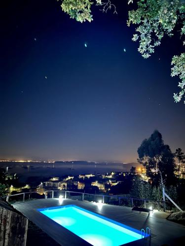 a swimming pool at night with a view of a city at Cabañas Rias Baixas in Pobra do Caramiñal