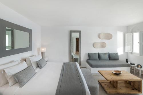 a white bedroom with a large bed and a couch at Aqua Luxury Suites by NOMÉE Hospitality Group in Imerovigli