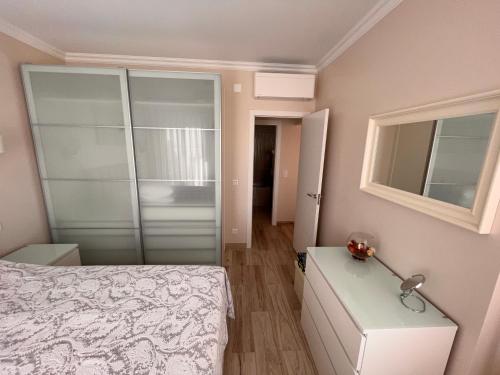 a bedroom with a bed and a glass closet at Costa de Caparica in Costa da Caparica