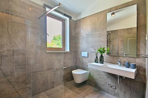 a bathroom with a sink and a toilet and a mirror at Villa Stoje - mit beheiztem Pool in Svetvinčenat