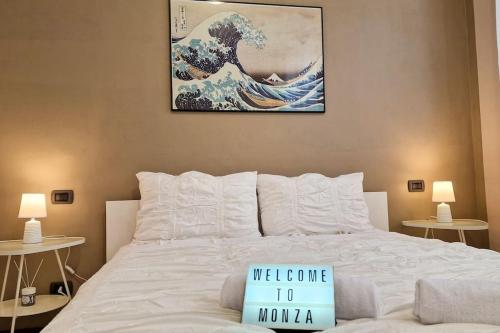 ein Schlafzimmer mit einem weißen Bett und einem Gemälde an der Wand in der Unterkunft MONZA CENTRO 5 Minuti POLICLINICO STADIO MONZA in Monza