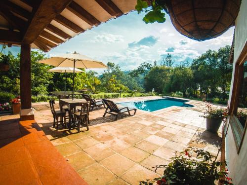 a patio with a table and an umbrella and a pool at Finca La Hacienda in El Retiro