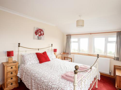 a bedroom with a white bed with red pillows at Pen Y Garth in Pwllheli