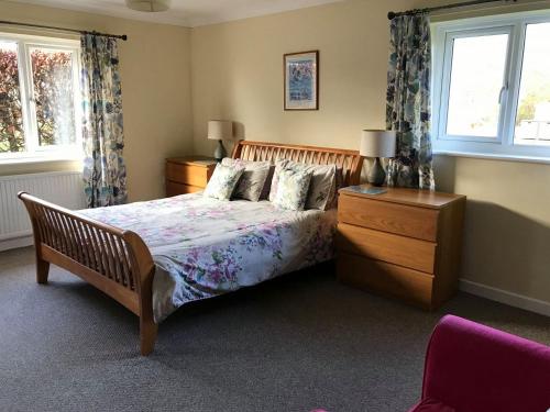 a bedroom with a bed and a dresser and two windows at Kestral in Welney