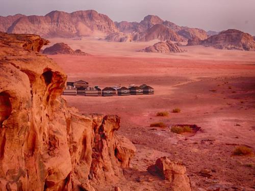 Wadi Rum Travel camp في وادي رم: منزل في الصحراء مع جبال في الخلفية