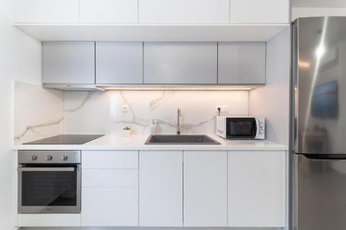 eine weiße Küche mit einer Spüle und einer Mikrowelle in der Unterkunft Lydia's Apartment in Iraklio
