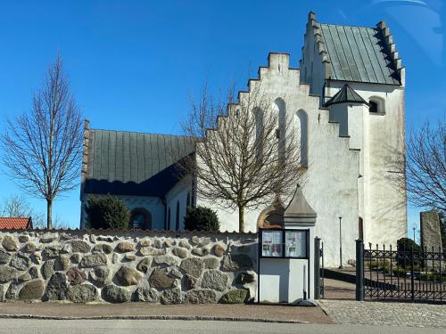 a church with a stone wall next to a building at Bli Hel in Malmö