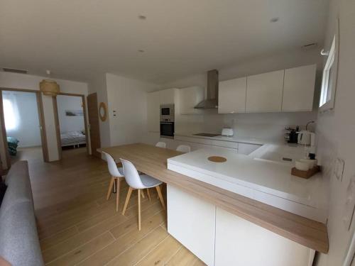 une cuisine avec des armoires blanches et une table et des chaises dans l'établissement Maison au calme avec piscine, à Carcans