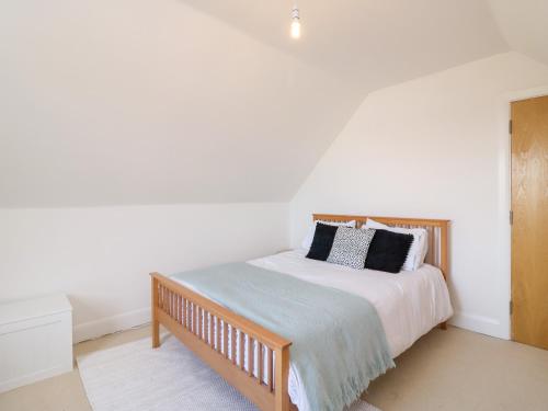 a white bedroom with a bed with a wooden frame at Bayview Loft in Weymouth