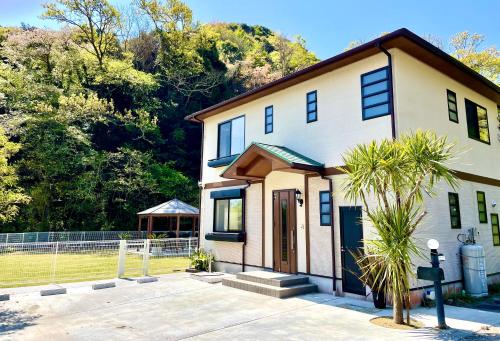 a house with a palm tree in front of it at 一棟貸別荘! Ohama Beach House & BBQ! 大浜海水浴場まで徒歩10分! Pets welcome! in Shimoda