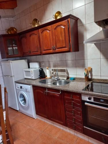 a kitchen with a sink and a washing machine at O Refúgio dos Pais in Bordeira