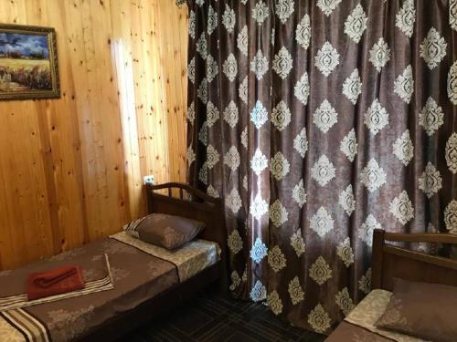 1 dormitorio con 2 camas y cortina en Бархат en Tsandrypsh