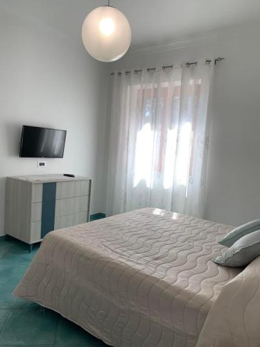 een witte slaapkamer met een groot bed en een televisie bij Casa Ausilia Trilocale in Amalfi