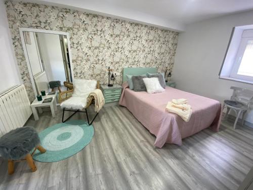 a bedroom with a bed and a chair and a mirror at Casa Los Cuncos in Barrio de Lomba