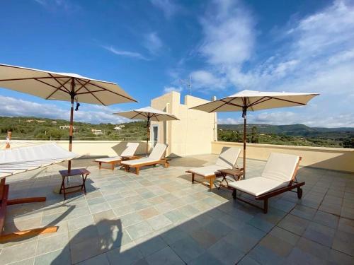 - un ensemble de chaises et de parasols sur une terrasse dans l'établissement Villa Boeddu, relax tra mare e campagna, à Alghero