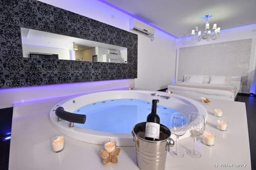 a room with a tub with a bottle of wine and candles at סוויטות כחול לבן - בקתות וסוויטות מושלמות עם ג'קוזי פרטי ובריכה מחוממת במתחם in Shahar