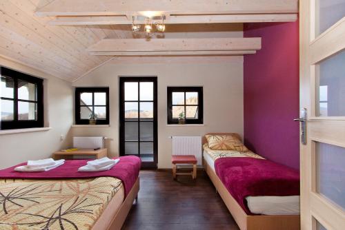 two beds in a room with purple walls and windows at Pokoje Gościnne Nad Zalewem w Starej Morawie in Stronie Śląskie