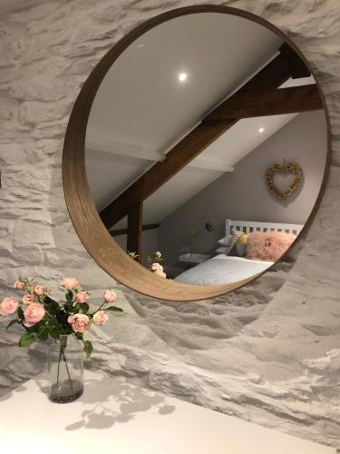 a bedroom with a circular mirror on a stone wall at 4 Quay View, Looe in Looe